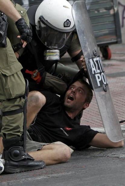 Un manifestante es reducido por la policía durante las protesta contra la visita de la canciller Angela Merkel.