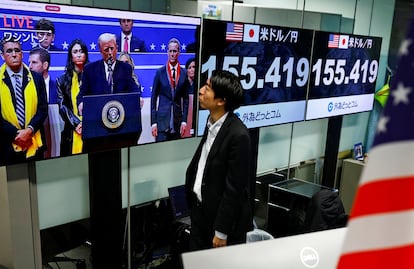 Un empleado de la casa de cambio japonesa Gaitame.com sigue la emisión por televisión de un discurso de Donald Trump, este martes en Tokio, junto a una pantalla con la cotización del dólar frente al yen.