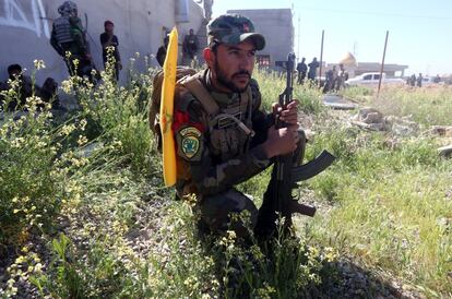 Un voluntario que apoya las fuerzas gubernamentales iraquíes en su lucha contra el Estado Islámico agachado junto a su arma en Tikrit.