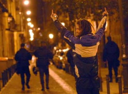 Un joven hace gestos obscenos a tres antidisturbios, de espaldas, en las proximidades de la plaza del Dos de Mayo la noche del miércoles.
