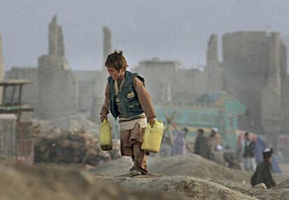Un niño afgano transporta agua en un descampado rodeado de ruinas del centro de Kabul.