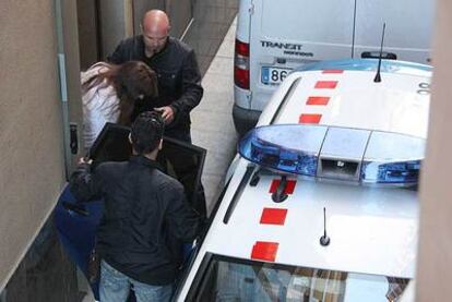 Dos <i>mossos</i> conducen a la presunta asesina hacia un vehículo policial.