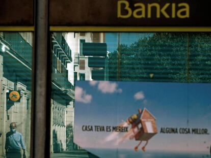 Vista de una oficina de Bankia y otra de CaixaBank reflejada en el cristal en el centro de L'Hospitalet (Barcelona)