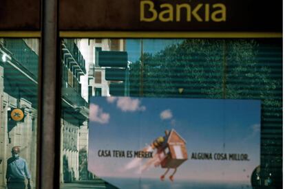 Vista de una oficina de Bankia y otra de CaixaBank reflejada en el cristal en el centro de L'Hospitalet (Barcelona)