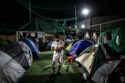 Un refugiado sostiene a un bebé en el campamento improvisado a las afueras de Mitilene, en Lesbos (Grecia).