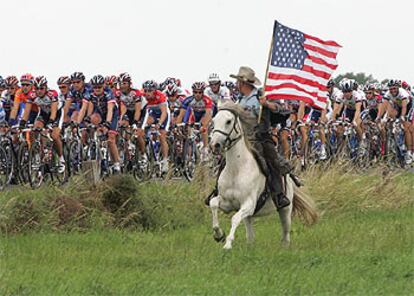 Un espectador, a caballo y con la bandera de Estados Unidos, anima el paso del pelotn.