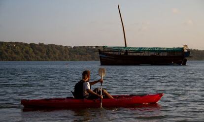 Louis Morice, uno de los padres del Musafir, navega con su canoa junto al barco en la bahía de Kilifi, Kenia.