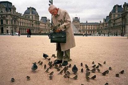 Un hombre da de comer a unas palomas frente al Museo del Louvre de París, en una imagen tomada en 2004.