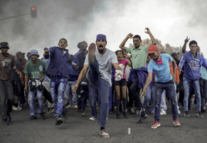 Manifestantes gritan consignas frente a una barricada en llamas en el municipio de Ennerdale, Johannesburgo (Sudáfrica). Las violentas protestas han estallado en la ciudad más grande de Sudáfrica por segundo día consecutivo.
