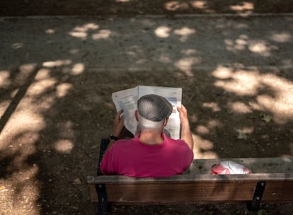 Un hombre leyendo un periódico en el parque Caramuel, en el barrio de Puerta del Angel, Madrid.