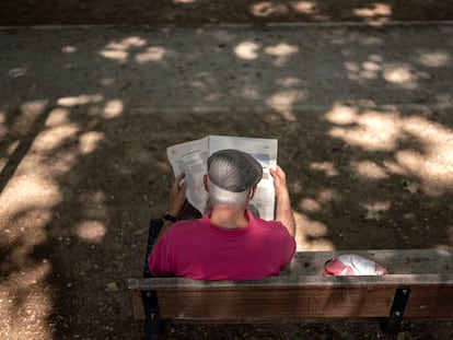 Un hombre leyendo un periódico en el parque Caramuel, en el barrio de Puerta del Angel, Madrid.