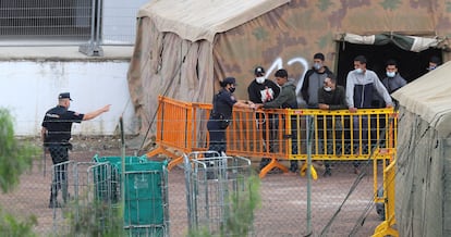 Varios inmigrantes hablaban ayer con agentes de la Policía Nacional en el campamento de atención temporal del antiguo polvorín de Barranco Seco.