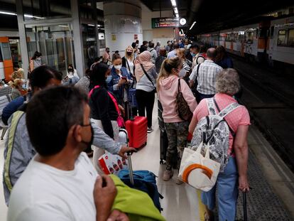 Decenas de pasajeros esperan en la estación de Sants en Barcelona la llegada de algún tren.