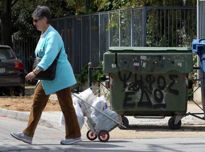 Una mujer pasa frente a un contenedor de basura con una pintada que dice: "Vote aquí".