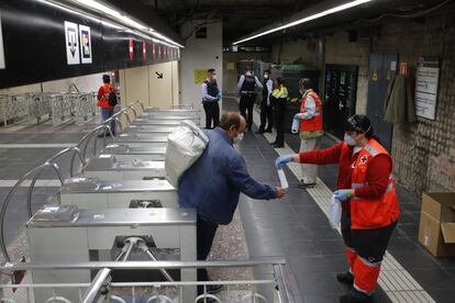 Voluntarios de Cruz Roja reparten mascarillas en el metro de Sants de Barcelona.