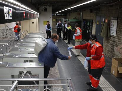 Voluntarios de Cruz Roja reparten mascarillas en el metro de Sants de Barcelona.