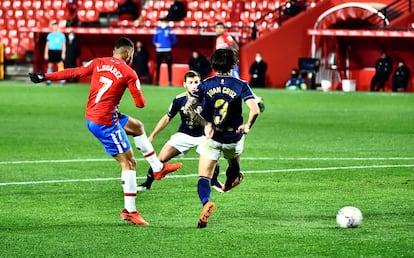 El delantero colombiano del Granada Luis Suárez intenta un lanzamiento ante dos rivales de Osasuna, durante el partido de LaLiga este martes en el estadio Nuevo Los Cármenes de Granada.
