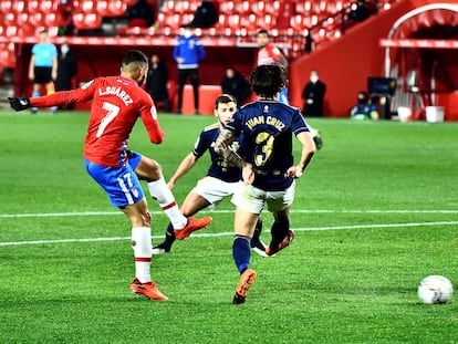 El delantero colombiano del Granada Luis Suárez intenta un lanzamiento ante dos rivales de Osasuna, durante el partido de LaLiga este martes en el estadio Nuevo Los Cármenes de Granada.