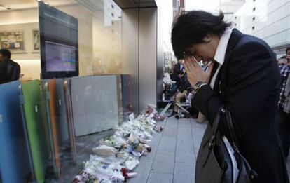 Un ejecutivo reza delante de las flores que se ofrecen en la memoria del cofundador de Apple, en la tienda de la compañía en Tokio