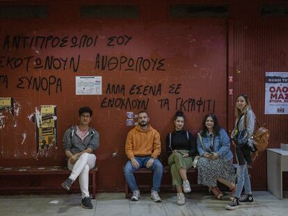 De izquierda a derecha: los estudiantes Stefanos, Alexandros, Eva, Mariana y Katerina, el jueves 18 de mayo en la facultad de Economía y Sociología de Atenas. La pintada de la pared dice: “Tus representantes matan a personas en las fronteras, pero a ti lo que te molesta son los grafitis”.