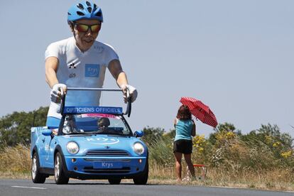 Un vehículo patrocinador pasa junto a una mujer durante la tercera etapa de la carrera ciclista Tour de Francia.