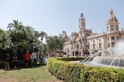 Varios turistas se protegen del calor a la sombra de varias palmeras este viernes 15 de agosto en la plaza del Ayuntamiento de Valencia.