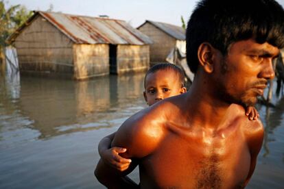 Un padre saca a su hijo de una zona inundada en Bogra (Bangladés).