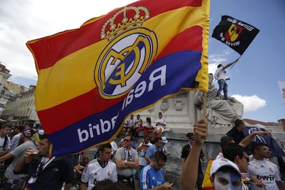 Un grupo de seguidores del Real Madrid ondean una bandera con los colores de España y el escudo de su equipo.