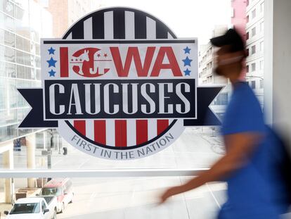 A pedestrian walks past a sign for the Iowa Caucuses on a downtown skywalk, in Des Moines, Iowa, on Feb. 4, 2020.