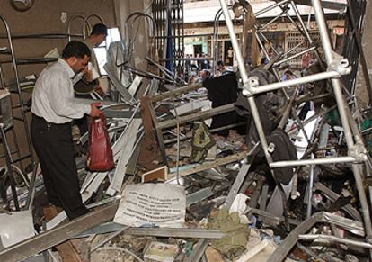 Familiares del dueño de una tienda buscan entre los escombros tras el atentado con explosivos ayer en el centro de Bagdad.