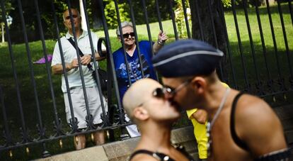 Una pareja de paseantes observa a los participantes de la marcha del Orgullo.