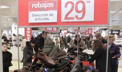 Varias personas miran zapatos en las rebajas de unos grandes almacenes.