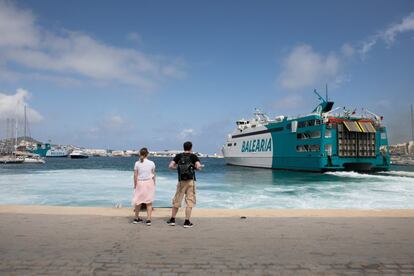 Unos turistas contemplan la salida de uno de los ferrys que atracan en Ibiza este jueves. Las islas tampoco han obtenido el aprobado del Gobierno británico para que sus compatriotas puedan viajar sin necesidad de guardar cuarentenas a su regreso.