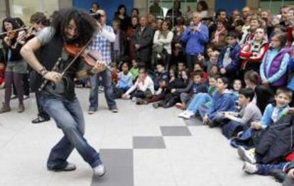 El violinista libanés Ara Malikian y su Orquesta en el Tejado, acompañados por un grupo de unos treinta alumnos del conservatorio "Jesús de Monasterio" de la capital cántabra, durante su actuación hoy en la estación de ferrocarril en Santander que se incluye dentro del Programa Estación Abierta Adif.