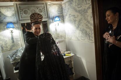 Una mujer coloca la mantilla a otra antes de que comience la procesión de la hermandad de la Exaltación de la Santa Cruz en Zaragoza (España).