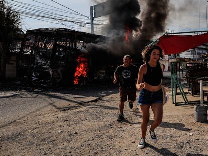 Transeúntes corren al lado de un camión que fue incendiado.