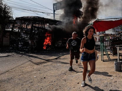 Transeúntes corren al lado de un camión que fue incendiado.