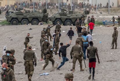 Soldados de la Legión Española utilizan sus defensas contra inmigrantes que acaban de cruzar la frontera en la playa del Tarajal.