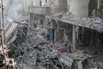Un  hombre camina entre los escombros de varios edificios destruidos en Gaza.