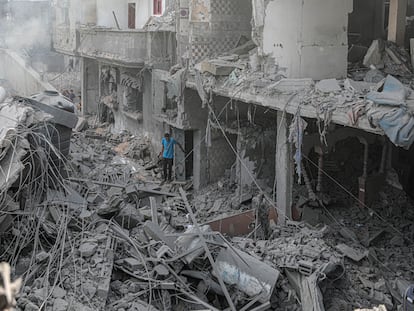 Un  hombre camina entre los escombros de varios edificios destruidos en Gaza.
