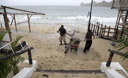 Dos hombre recogen la arena de la playa acumulada en un restaurante en Cabo San Lucas, México, el 6 de septiembre.