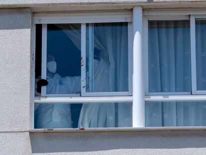 Un agente de la policía nacional corre una cortina en la vivienda del suceso en Úbeda (Jaén), este domingo.