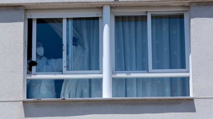 Un agente de la policía nacional corre una cortina en la vivienda del suceso en Úbeda (Jaén), este domingo.