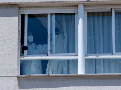 Un agente de la policía nacional corre una cortina en la vivienda del suceso en Úbeda (Jaén), este domingo.