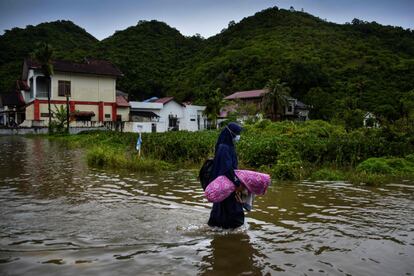 Una mujer vadea las aguas tras las fuertes lluvias en la zona residencial de Ajun, en las afueras de Banda Aceh (Indonesia).