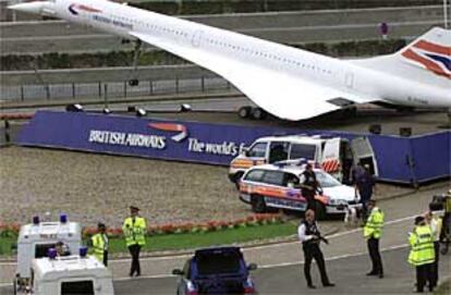 Policías británicos armados cubren a miembros de su equipo que realizan controles en coches a la entrada del aeropuerto de Heathrow.