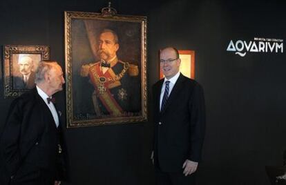 El príncipe Alberto de Mónaco (derecha) y Vicente Zaragüeta, posan junto al retrato del tatarabuelo del soberano monegasco, en el Aquarium de San Sebastián.