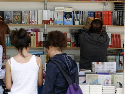 Un grupo de jóvenes examina libros en una caseta de la feria de Valencia.