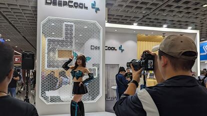 A man takes a photo of a girl at a Computex booth.