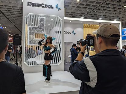 A man takes a photo of a girl at a Computex booth.